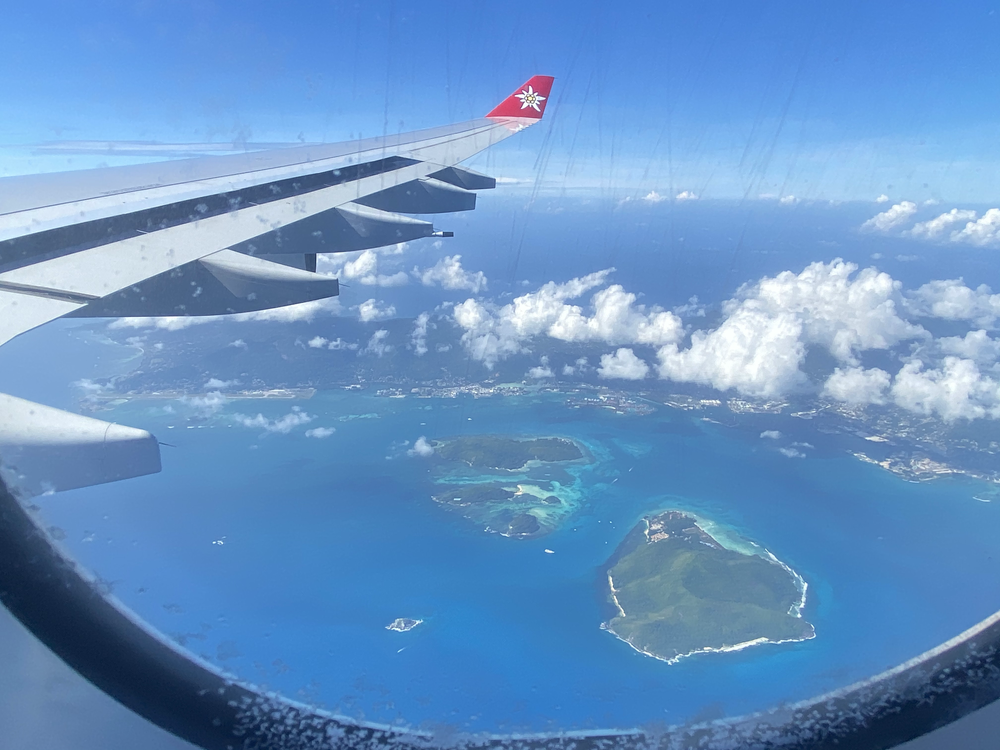 Blick aus dem Flugzeugfenster auf Inseln im Meer